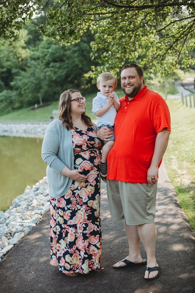 A photo of a pregnant Jennifer, her husband Derek, and her son standing alongside a lake.